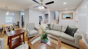 A living room with a sofa, armchair, coffee table, and a ceiling fan.
