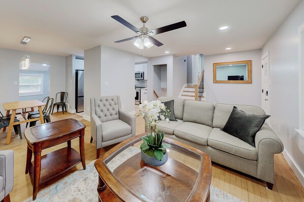 A living room with a sofa, armchair, coffee table, and a ceiling fan.