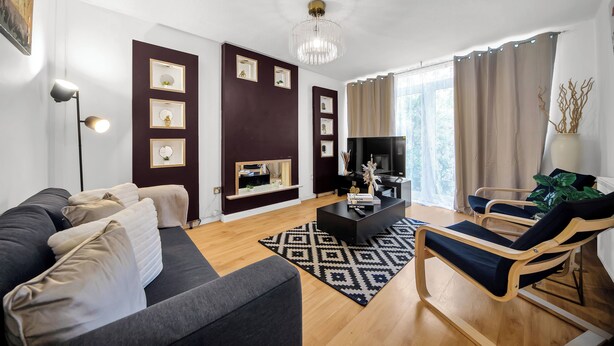 Una sala de estar moderna con un sofá oscuro, una mesa de centro y un televisor.