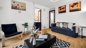 Una sala moderna con sofá, sillón, mesa de centro y obras de arte en las paredes.