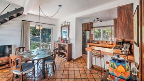 Una cocina amplia con comedor, que cuenta con una isla grande, armarios de madera y vistas al exterior.