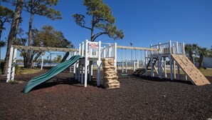 A playground with a slide, climbing wall, and swings.