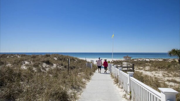 A pathway leading to a beach with a clear sky.