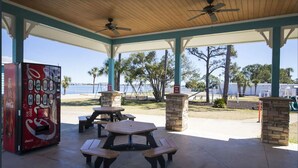An outdoor covered patio with picnic tables and a Coca-Cola vending machine.