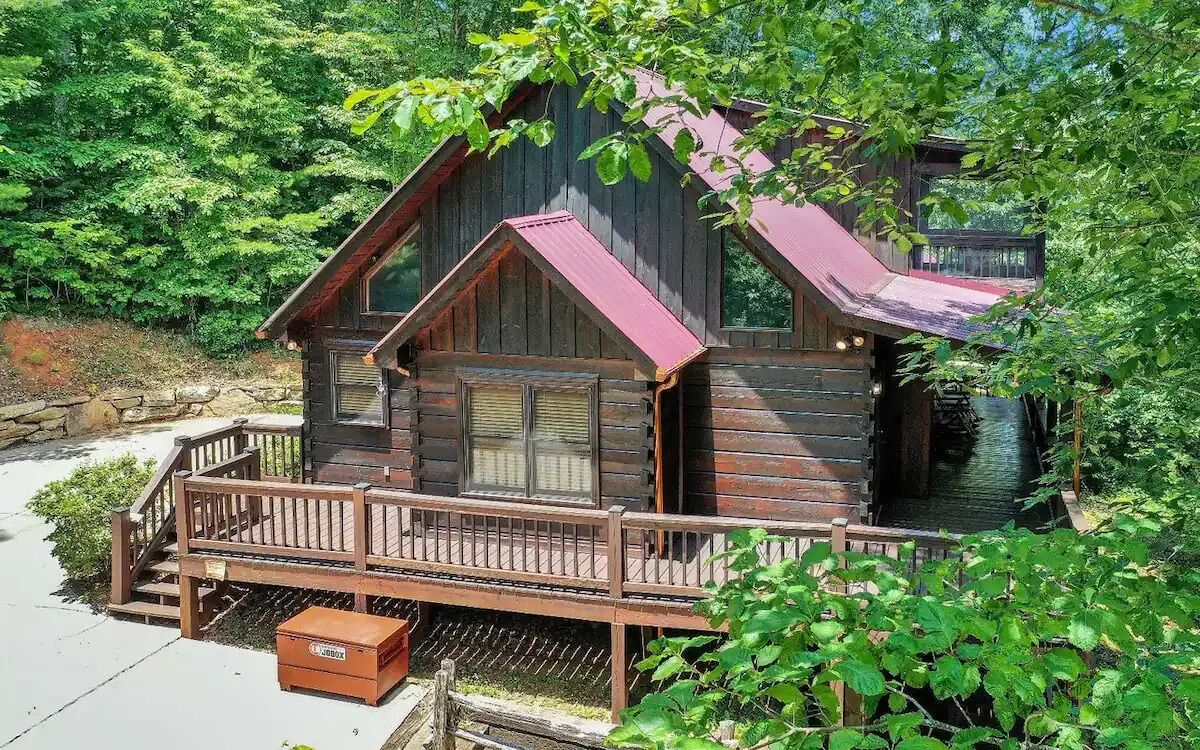 Eine rustikale Holzhütte mit Ziegeldach und einer Holzterrasse mit einer Bank.