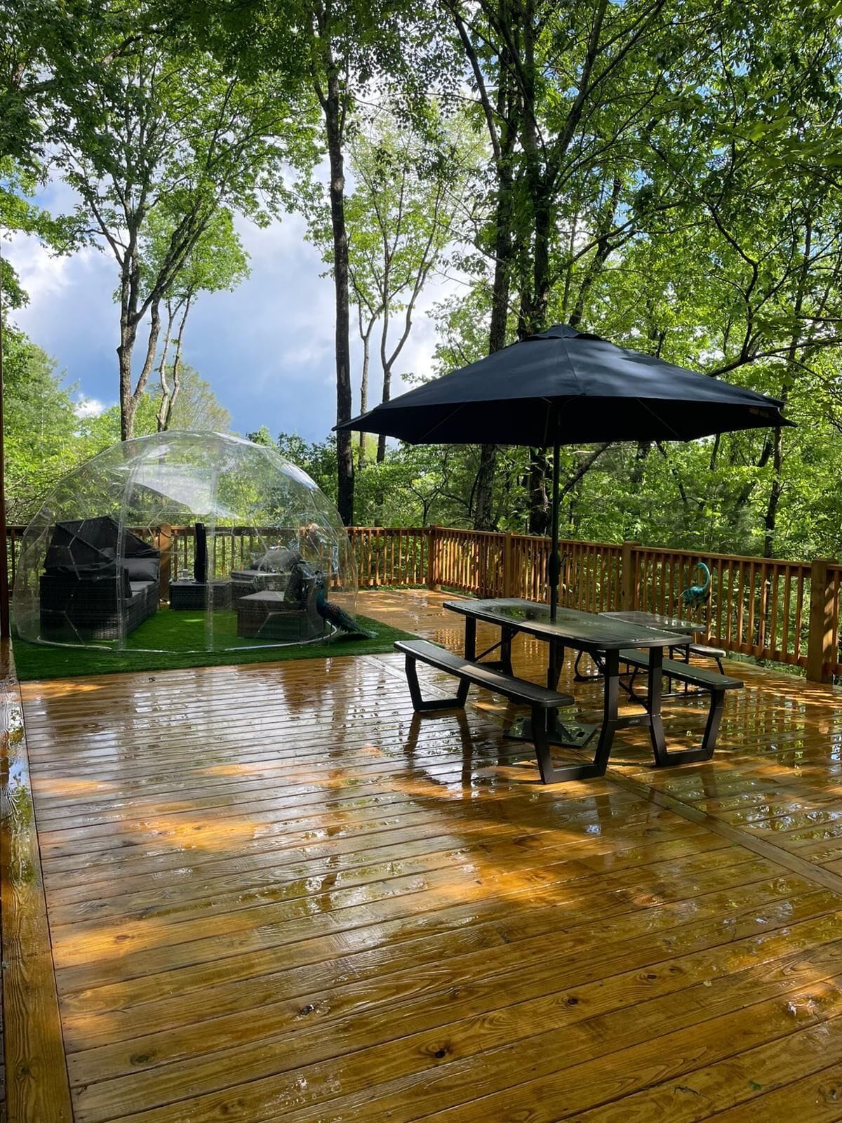 A wooden deck with a picnic table and umbrella, surrounded by trees.