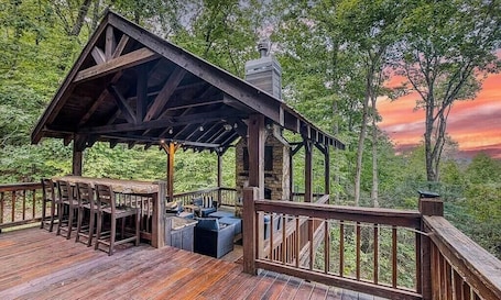 A wooden deck with outdoor seating and a covered area.. Close to Downtown • Luxury Cabin • Hot Tub • GeoDome and More!
