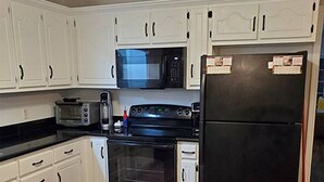 A kitchen with white cabinets, a black refrigerator, a microwave, a toaster, and an oven. - Conveniently Located 2B/2BA Very Close to University of Alabama Campus (Tuscaloosa)