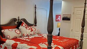 A four-poster bed with a red and white quilt, a ceiling fan, and a door with a picture frame. - Conveniently Located 2B/2BA Very Close to University of Alabama Campus (Tuscaloosa)
