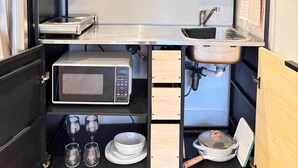 A compact kitchen with a built-in microwave, sink, and storage cabinets.