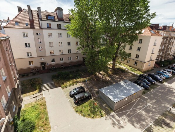 A multi-story residential building with a parking area and a small garden.