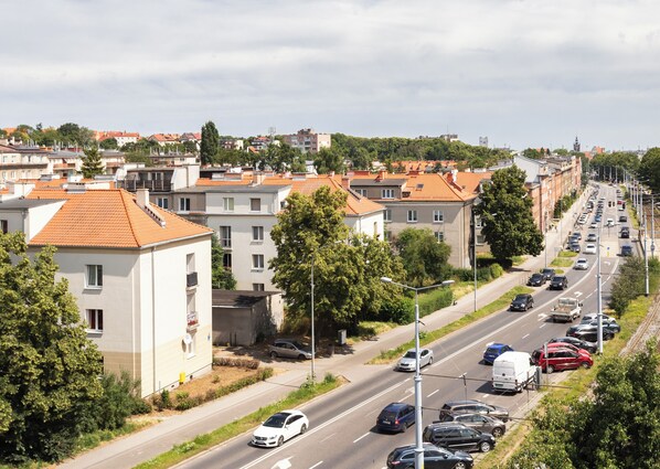 A residential street with multi-story buildings, parked cars, and a clear sky.