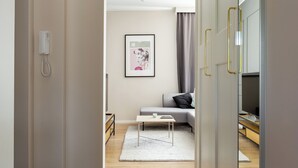 Una sala de estar moderna con un sofá gris, una mesita blanca y una obra de arte enmarcada en la pared.