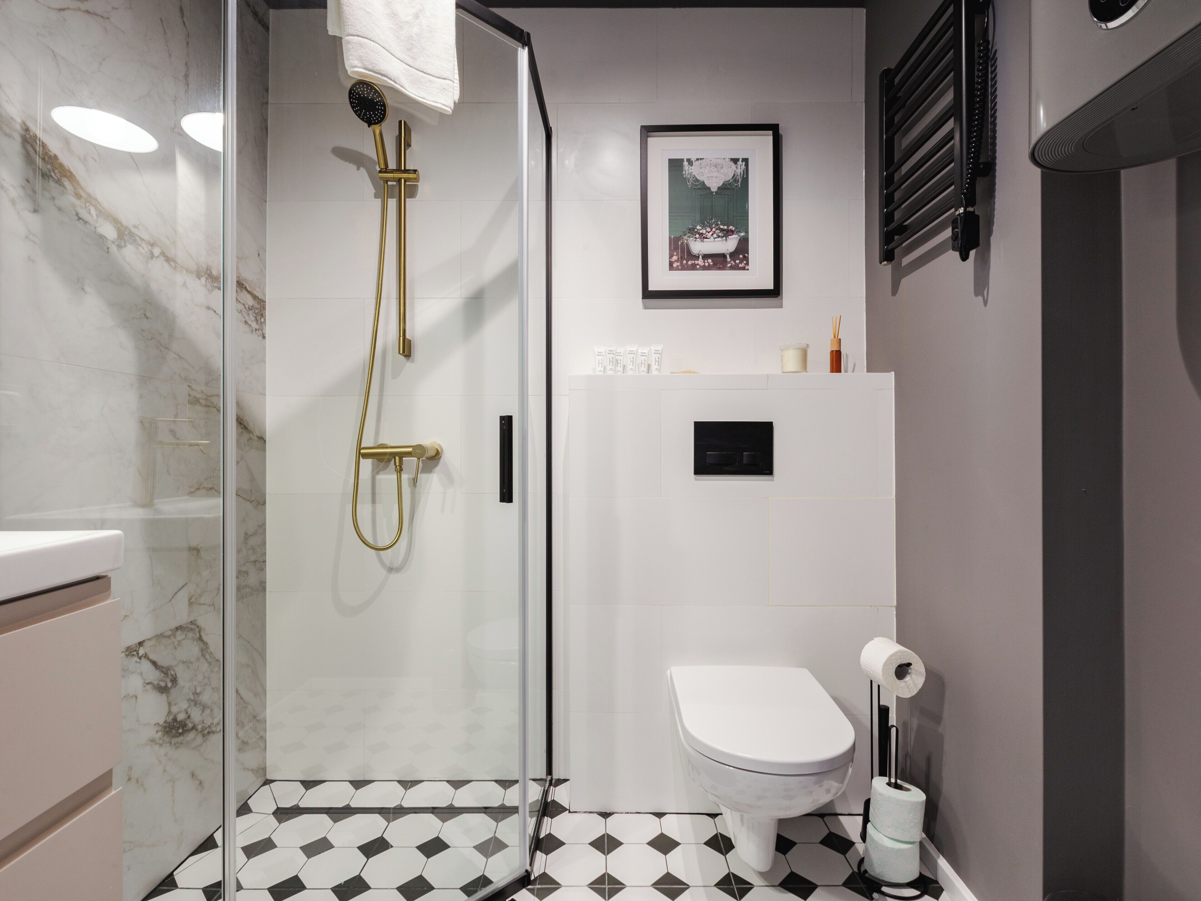 Un bagno moderno con doccia vetro, un water bianco e un pavimento a motivi bianco e neri.