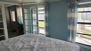 Ein Schlafzimmer mit einem großen Bett, einem Kleiderschrank und Blick ins Freie.