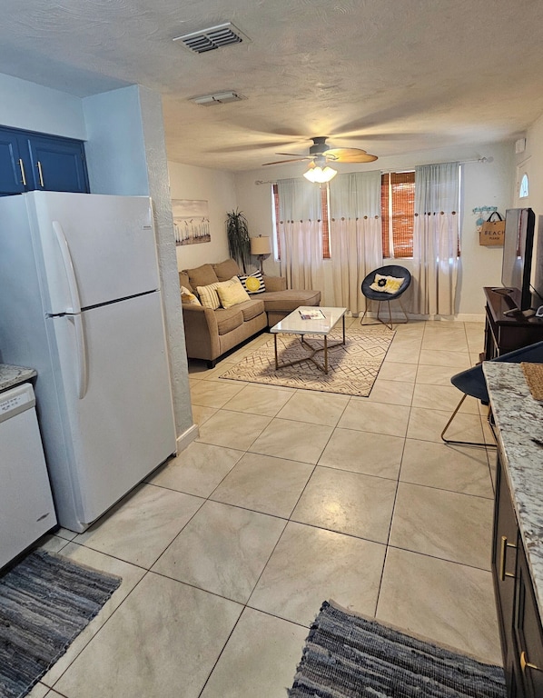 A compact living space with a kitchenette, a sofa, a coffee table, and a ceiling fan. - Charming 3-bedroom house with AC,WiFi, private backyard and more in Ormond Beach (Ormond Beach)