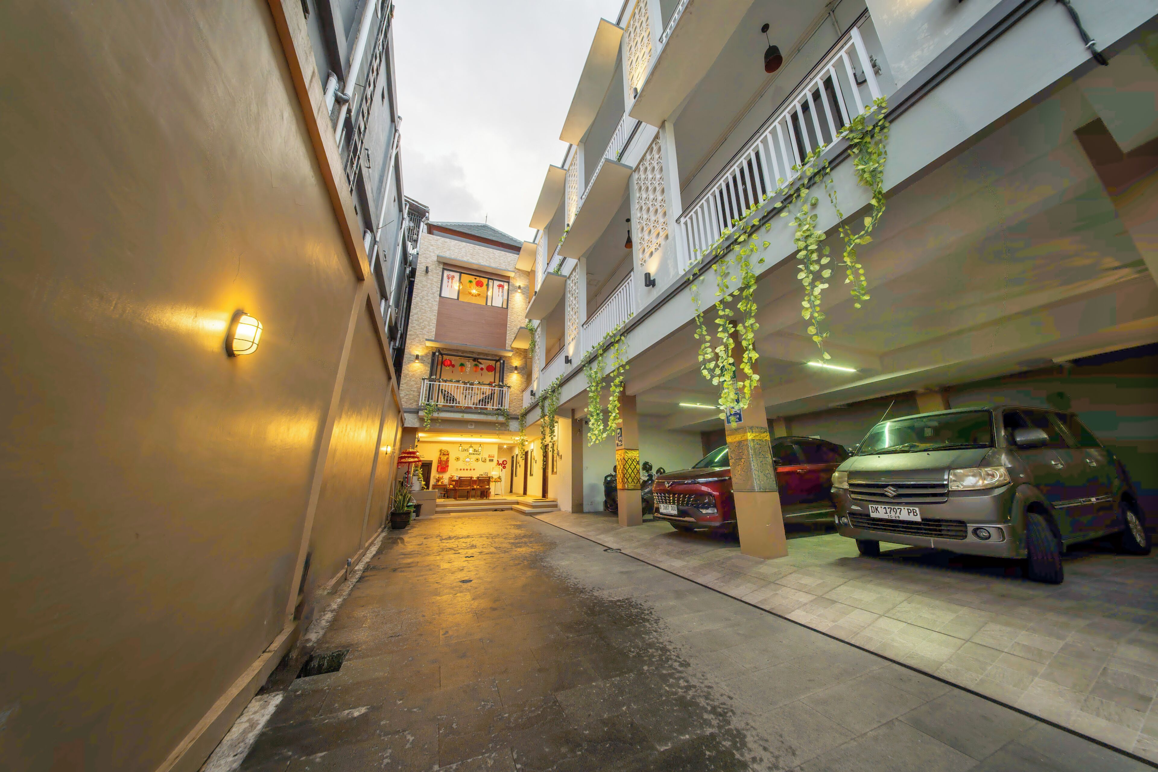Un estrecho callejón con un edificio a un lado y una zona de estacionamiento al otro.