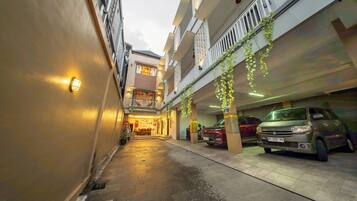 Un estrecho callejón con un edificio a un lado y una zona de estacionamiento al otro.