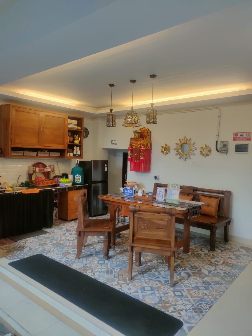 A compact kitchen with wooden cabinets, a dining table with chairs, and a refrigerator.