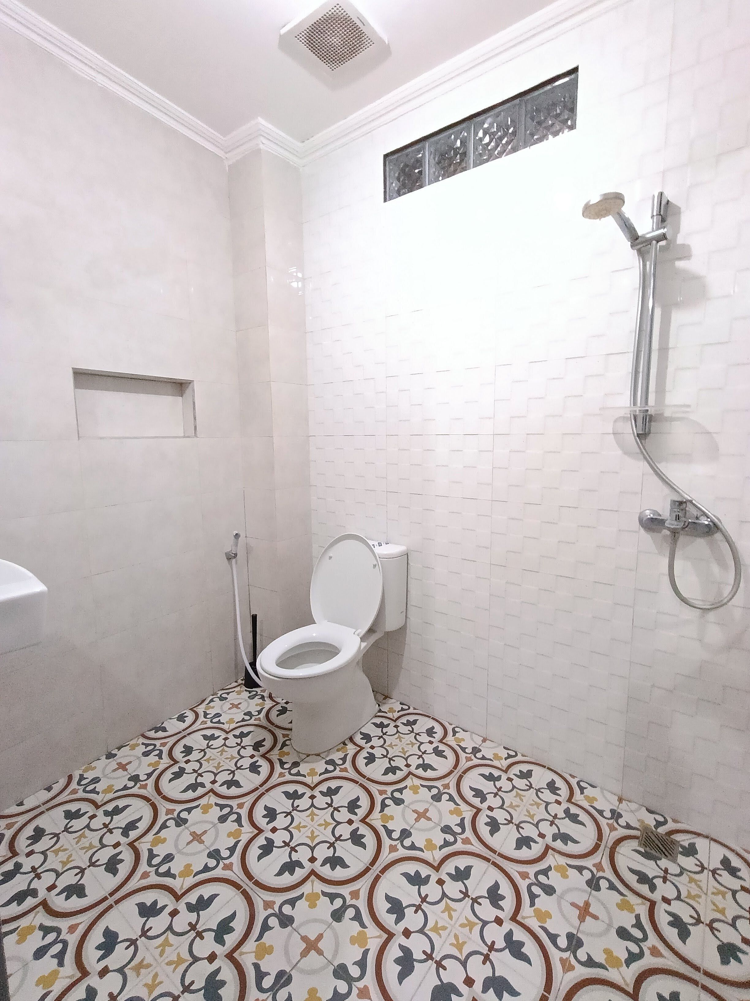 A bathroom with a toilet, shower, and patterned floor tiles.