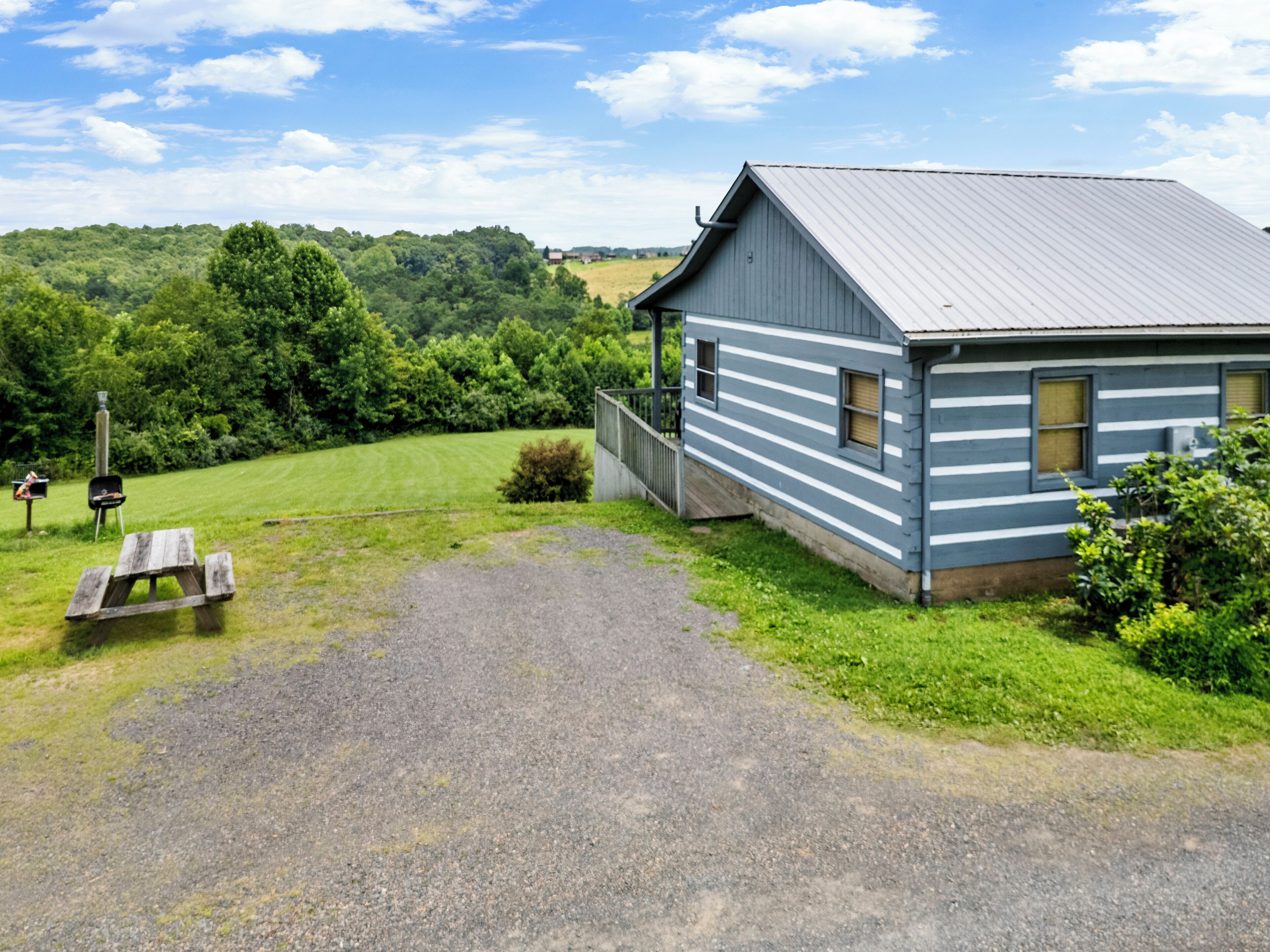 A small, single-story building with a metal roof, situated in a grassy area with a gravel path leading to it.
