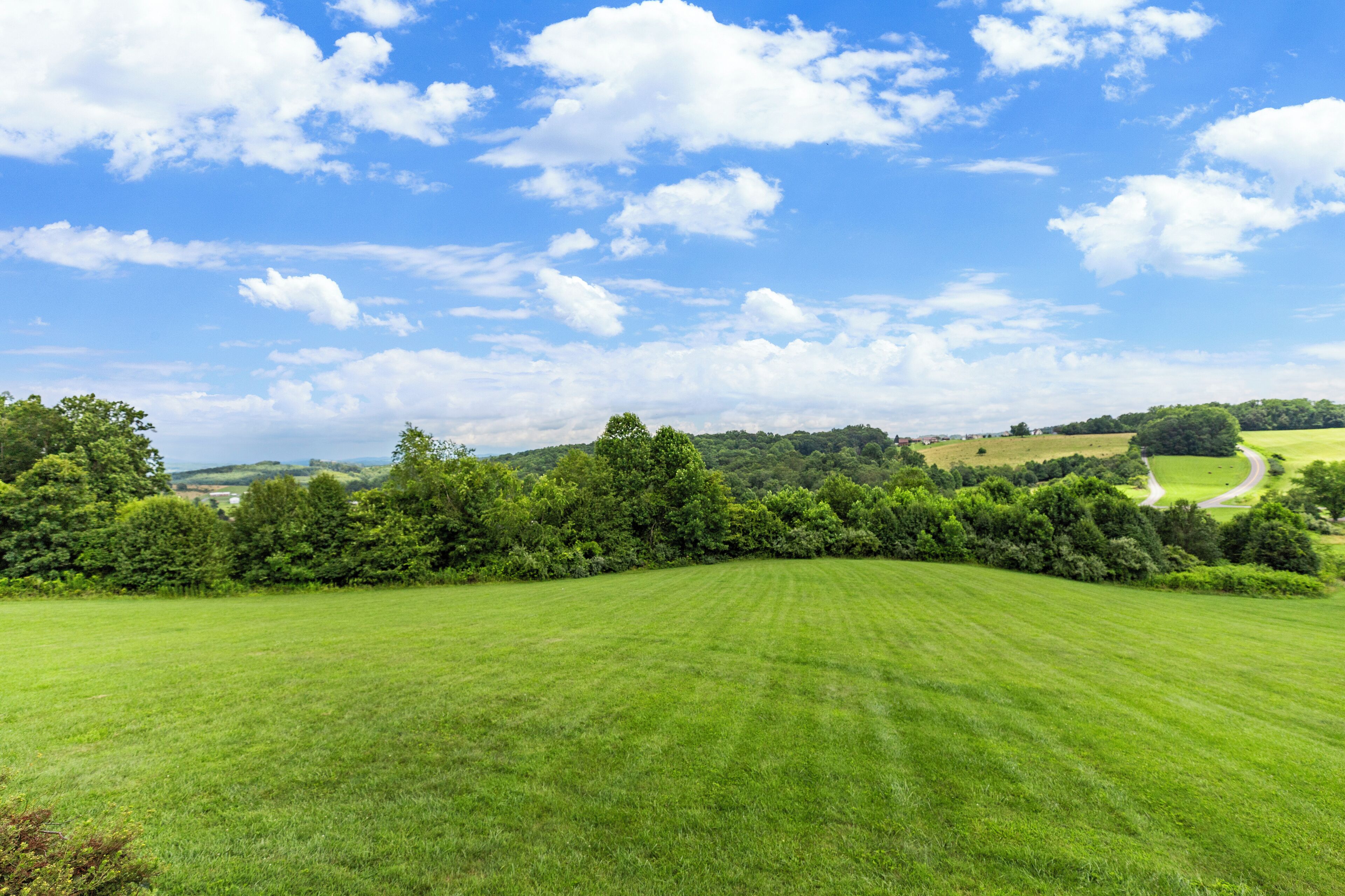 A wide, open field with a clear sky and scattered clouds.