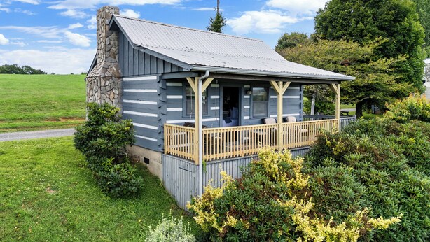 Ein rustikales Blockhaus mit einem Steinkamin, einer Holzterrasse und einem gepflegten Rasen.