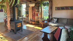 Una sala de estar acogedora con una estufa de leña, muebles de madera y diversas plantas.