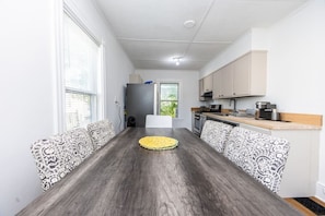 Una cocina compacta con una isla central, muebles blancos y un ventanal que aporta luz natural.