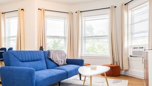 Una sala de estar moderna con un sofá azul, una mesita blanca y un tapete beige.