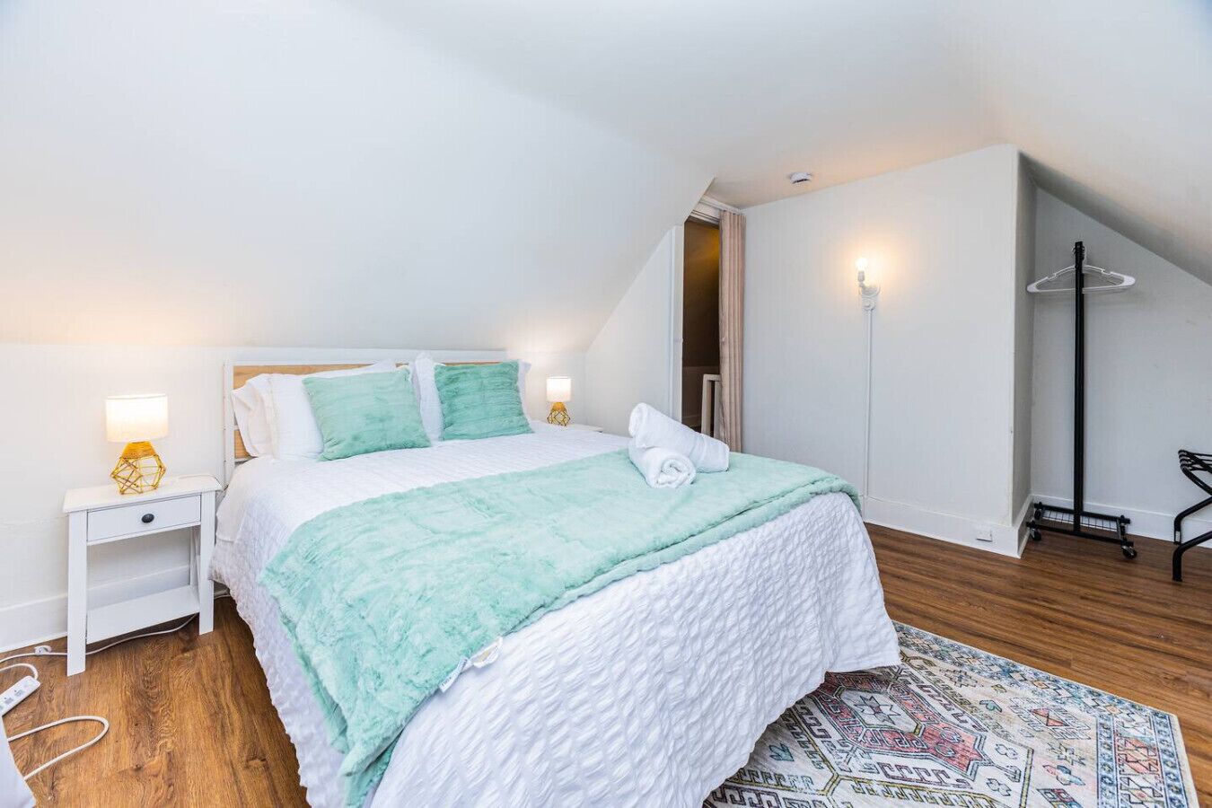 Een slaapkamer met een bed, nachtkastjes, een lamp, een vloerlamp en een kamerkleed met dessin.