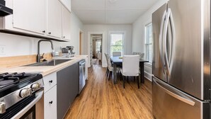 Una cocina moderna con electrodomésticos de acero inoxidable, piso de madera y comedor con mesa y sillas.