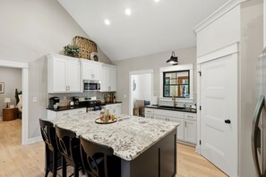 Une cuisine moderne avec des meubles blancs, un îlot central et un coin repas avec des chaises.