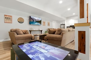 A modern living room with two sofas, a coffee table with a digital display, and a large framed picture on the wall.