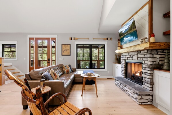 A spacious living room with a stone fireplace, a leather sofa, and a wooden coffee table.