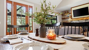 Comedor con una mesa dispuesta para cuatro, con platos, tazones y una vela.