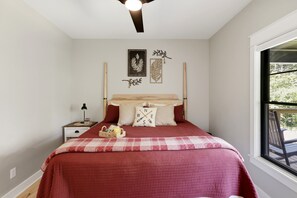 Une chambre à coucher avec un lit, une table de chevet, une lampe, une fenêtre et des éléments décoratifs sur les murs.