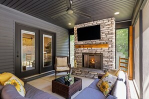 A modern living room with a stone fireplace, comfortable seating, and a large TV mounted on the wall. - Private Nolin Lake Home with FirePit, Ice Maker, Arcade & Electronic Game Table. (Clarkson)