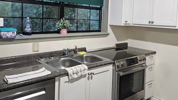 A kitchen with a window, stainless steel appliances, and white cabinets.