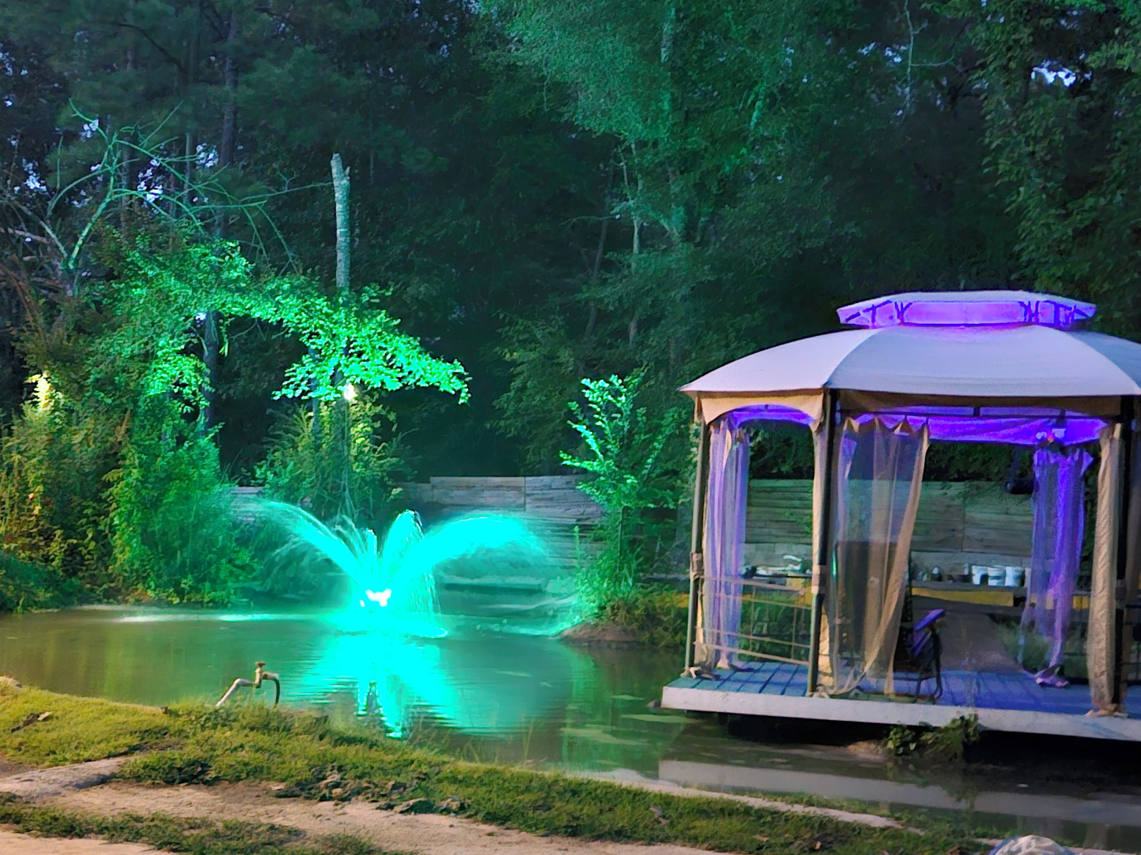 A gazebo with a water feature in a forested area.