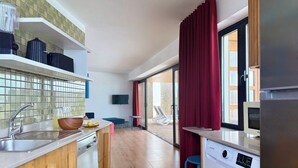 Een moderne keuken met een wasmachine, een spoelbak en een aan de muur bevestigde televisie.