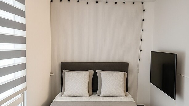 A modern bedroom with a large bed, a bench, a TV, and a window with blinds. - Studio Near LDLC ARENA OL (Décines-Charpieu)