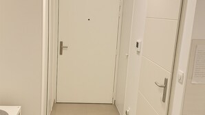 A hallway with a white door, a small table with a white surface, and a white shelf unit. - Studio Near LDLC ARENA OL (Décines-Charpieu)