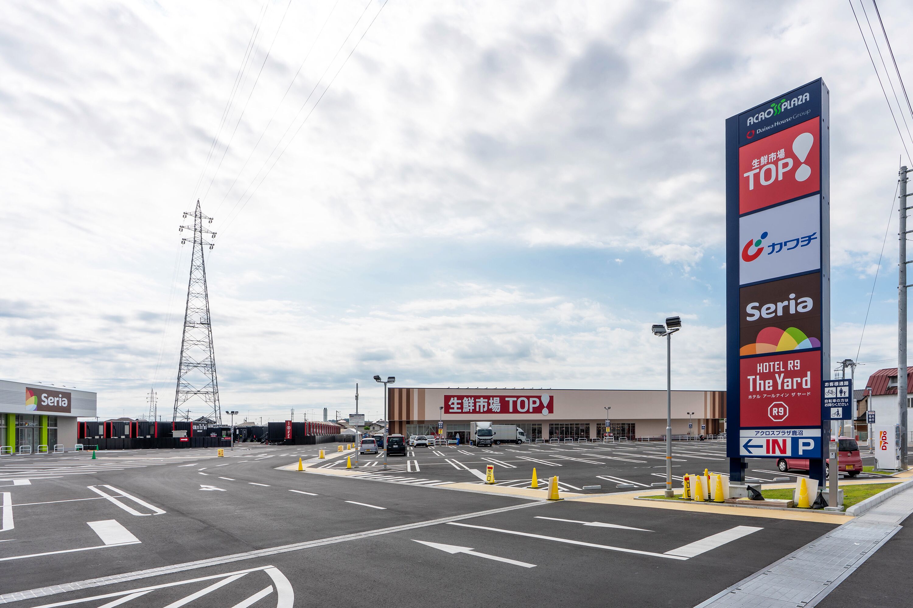 A parking lot with a large sign for a shopping plaza and a hotel.