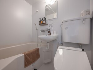 Een bad/douchecombinatie, een haardroger, handdoeken, shampoo