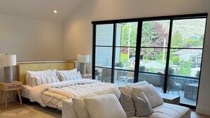 Une chambre moderne avec un grand lit, un canapé et une vue sur l’extérieur.