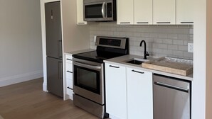 Une cuisine moderne avec des armoires blanches, des appareils en acier inoxydable et un plancher en bois.