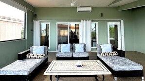 A spacious room with a ceiling fan, two sofas with cushions, a small table, and a sliding glass door leading outside.