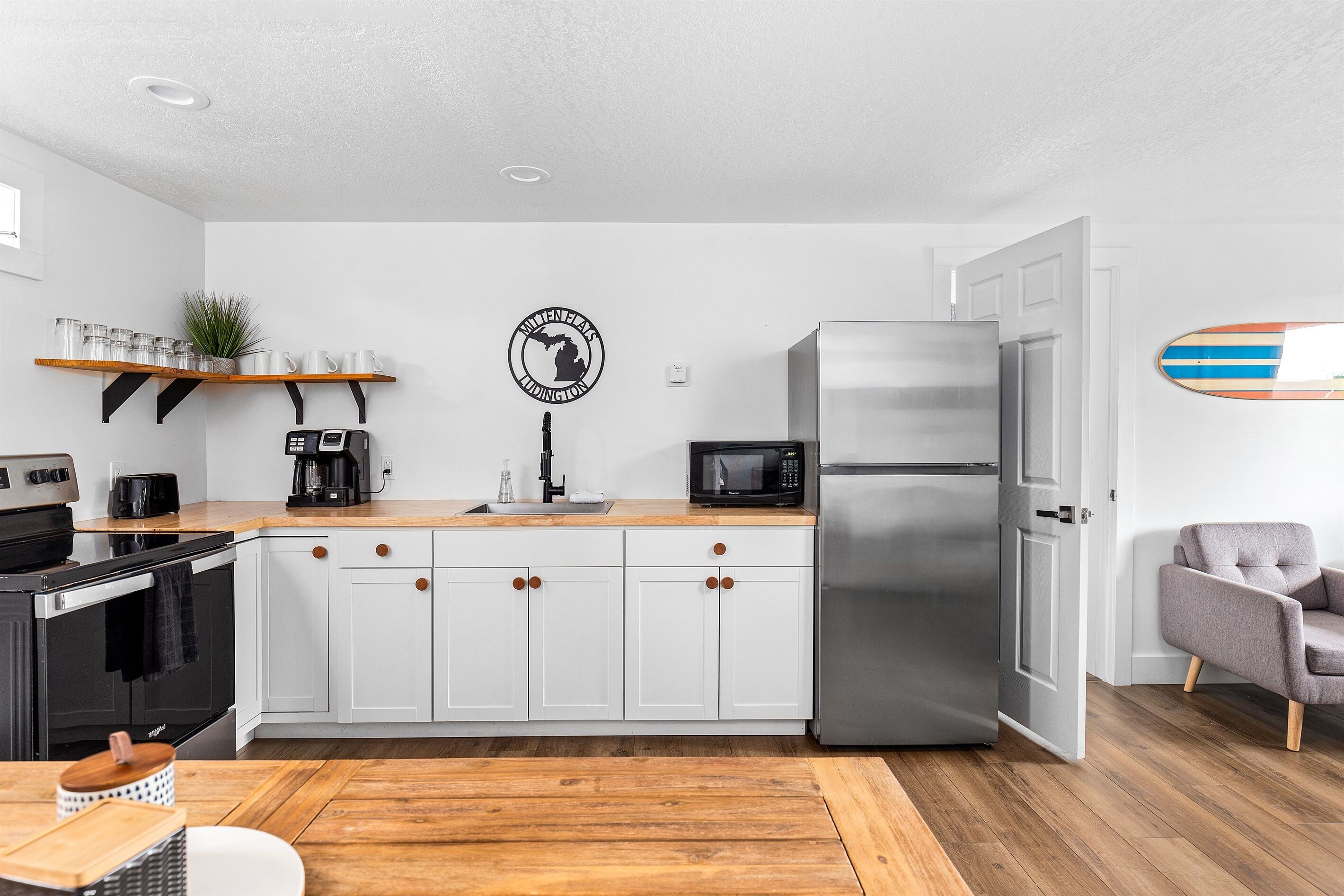 A modern kitchen with white cabinets, a stainless steel refrigerator, a microwave, and a coffee maker.