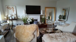 A living room with a fireplace, a television, and a dining area with a round table.